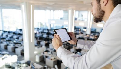 Man using a tablet and looking down at the trading room floor