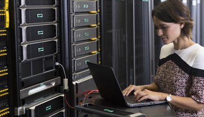 Woman using a laptop to work on a server rack